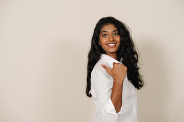 Young brunette indian woman smiling at camera and gesturing aside