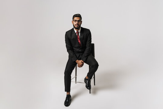 Young indian man wearing suit posing while sitting on chair