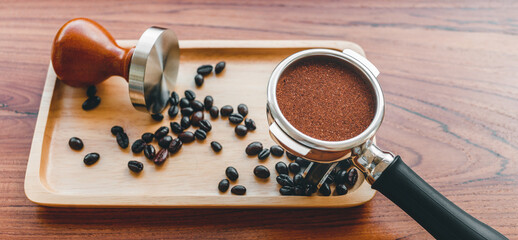 Equipment of barista coffee tool tamper and tempered coffee in portafilter roasted coffee beans on wooden table