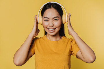 Young asian woman wearing t-shirt smiling while listening music