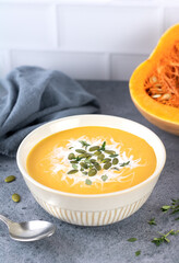 Pumpkin soup with a creamy texture and pumpkin seeds on a dark gray background.