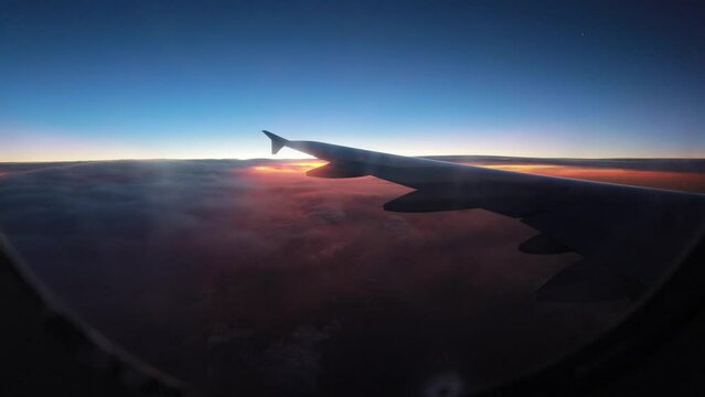 Morning view of the sunrise through the window during the airplane flight. The plane wing among the clouds