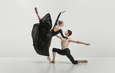 Young man and woman, ballet dancers performing isolated over grey studio background. Noble, pride dance