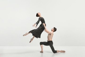 Young man and woman, ballet dancers performing on stage isolated over grey studio background. Support © master1305