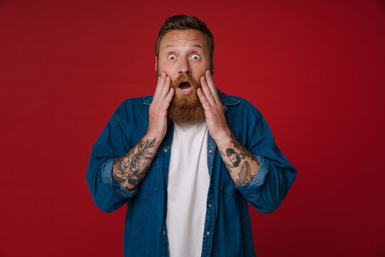 Adult bearded tattooed handsome shocked redhead man with opened mouth