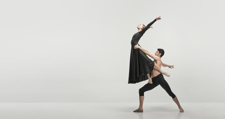 Young man and woman, ballet dancers performing isolated over grey studio background. Support and fly. FLyer