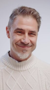 Portrait of happy casual older man looking at camera, smiling, wearing white pullover on cold winter day. Mid adult, mature age caucasian man on white background.