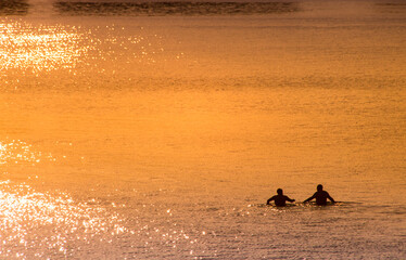 couple en train de se baigner dans la mer le soir avec un coucher de soleil