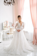 Fototapeta na wymiar beautiful bride in an expensive wedding dress in full growth posing in a bright interior