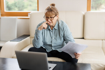 Active mature woman using a laptop for remote work from the home office. Video conference, video meeting. Senior teacher leads webinar