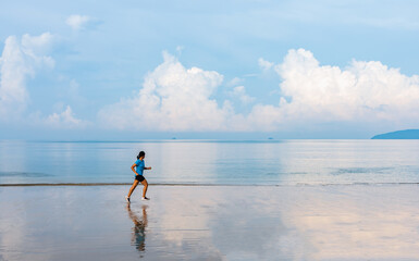 Woman running along the beach of the sea with beautiful sky and blue sea background.