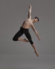 Portrait of young muscular man, ballet dancer performing isolated over dark grey studio background. Expressing freedom