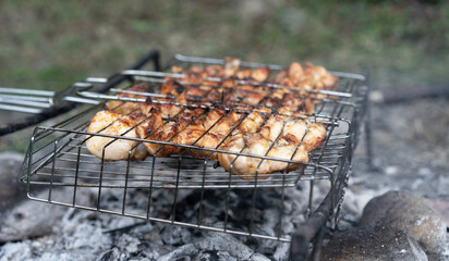Chicken pieces are cooked on a charcoal grill