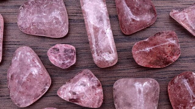 Strawberry quartz rare jewel stones texture on brown varnished wood background. Moving right seamless loop backdrop.