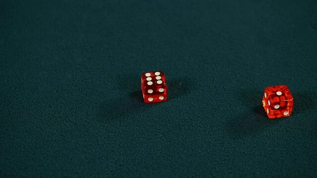 Red casino dice being rolled and settling on seven on green casino gaming table, Craps, Slow motion 