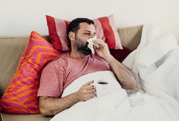 Hombre con un resfriado y positivo de coronavirus, bebiendo un te - obrazy, fototapety, plakaty