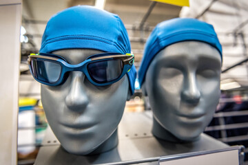 Goggles and a swimming cap on the heads of mannequins