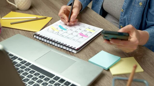 The concept of planning in the diary of events and meetings. A woman writes notes on a calendar.