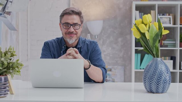 Bearded Man Working Online With Laptop Computer At Home Sitting At Desk. Home Office, Browsing Internet, Study Room. Portrait Of Mature Age, Middle Age, Mid Adult Man In 50s.