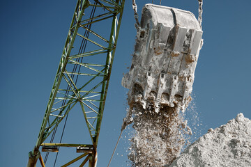 Pouring chalk out of chalk dragline out of bucket at quarry