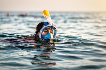 Young woman swimming in the sea with modern snorkeling gear. Full face snorkeling mask. Summer...