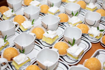 Cakes and snacks are placed on trays with several cups of coffee and served during hotel breaks or banquets.