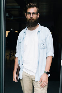 Portrait of confident male programmer standing at doorway in startup company