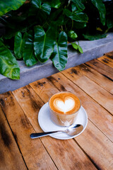 glass of cappuccino on wooden background with beautiful latte art of heart shape. love concept