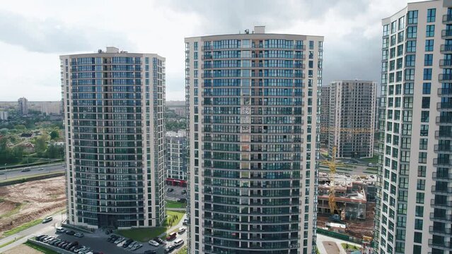 Aerial view of the blocks of high-rise buildings in the new microdistrict and the panorama of the city on a cloudy summer day