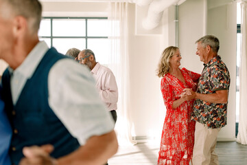 Smiling senior men and woman dancing together in class
