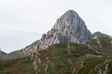 Beautiful view of the peak of a rocky and steep mountain with great vegetation in the lower part in Valle de Anciles, León, Spain
