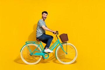 Side profile photo of young crazy positive good mood day man riding new bicycle rent chill hobby weekend isolated on bright yellow color background