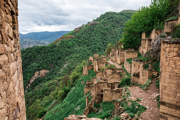 An ancient non-residential, stone city high in the Gamsutl mountains, against the backdrop of large, high mountains.