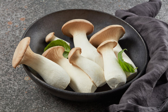 King Oyster mushrooms or Eringi in a black bowl on a dark background. Shallow depth of field