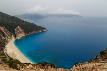 Fototapeta na wymiar Top view at Myrtos Beach from road during bad weather conditions, thunderstorm and rain, with low dark clouds over sea. Cephalonia, Greece