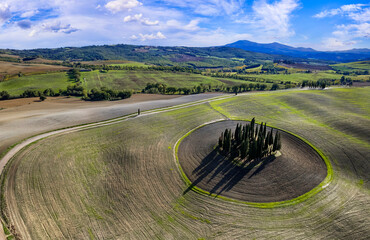 Italy landscape. Amazing Tuscany scenery. Typical countryside with vast fields of Val d'Orcia famous beautiful valley. Aerial drone shot of circle cypresses trees, high angle view - obrazy, fototapety, plakaty