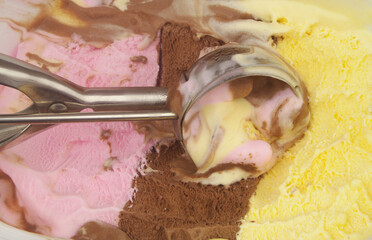 Ice-cream scoop close up and Neapolitan ice cream - vanilla, strawberry and chocolate.
