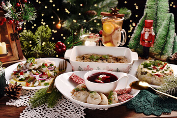 Fototapeta na wymiar Christmas Eve red borscht with ravioli and other dishes on festive table