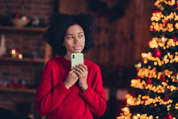 Portrait of minded peaceful small girl hold telephone contemplate idea plan imagine christmastime spirit indoors