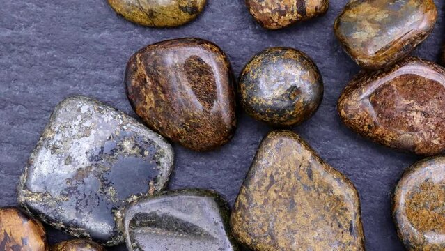 Bronzite heap up jewel stones texture on black stone background. Moving right seamless loop backdrop.
