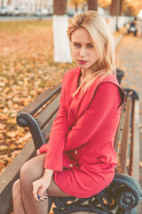 Obraz na płótnie Canvas Portrait of a blonde next to a red-orange bush in autumn. The concept of the autumn season