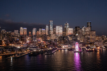 night aerial view of illuminated Seattle Downtown and the Waterfront pier area with The Seattle Great Wheel - aerial night view  	