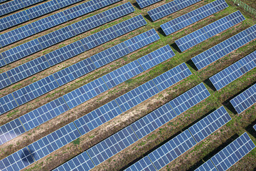 Aerial view of solar power plant on green field. Electric panels for producing clean ecologic energy.