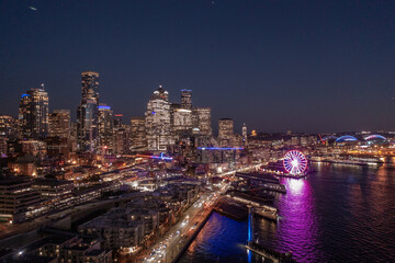 night aerial view of illuminated Seattle Downtown and the Waterfront pier area with The Seattle Great Wheel - aerial night view  	