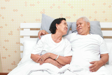 Asian elderly couple lying in bed in the bedroom Happy smile. family concept health care, health insurance for seniors