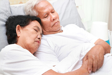 Fototapeta na wymiar An elderly Asian couple sleeps cuddling in bed in the bedroom. family concept health care, health insurance for seniors