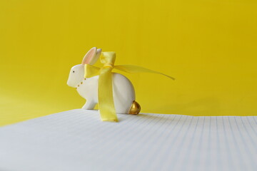 white rabbit on a white sheet of paper, yellow background, symbol of the new year