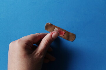 a brown patch on the thumb, a woman's hand, a used patch in blood on a blue background
