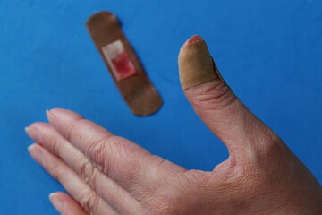 a brown patch on the thumb, a woman's hand, a used patch in blood on a blue background
