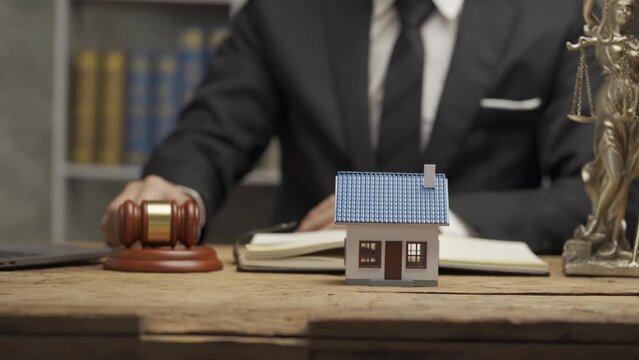 house auction idea, businessman holding a hammer and a house next to it Close-up of lawyer hand holding real estate hammer house and building idea at the office.